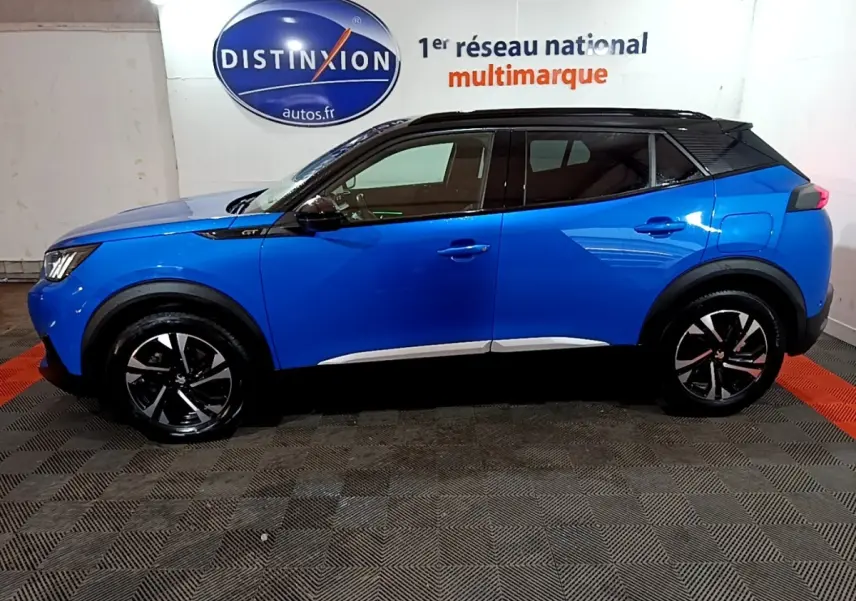 Vue de profil côté gauche d’un Peugeot 2008 Bleu GT 2021 avec toit noir et jantes alliage noires.