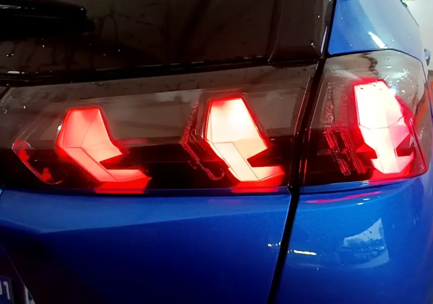 Gros plan sur les feux arrière allumés côté gauche d’un Peugeot 2008 bleu version BlueHDi 130 GT de 2021.