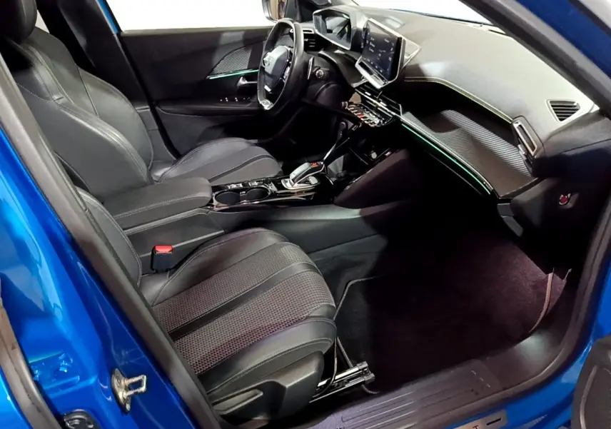 Vue intérieure côté conducteur du Peugeot 2008 bleu 2021, avec tableau de bord numérique et sièges en cuir noirs.