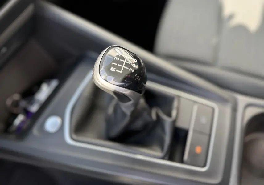 Gros plan sur le levier de vitesses manuel noir de la Volkswagen Golf 1.0 TSI 110 Life, intérieur tissu gris.