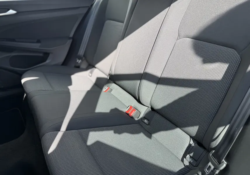 Vue intérieure sur les sièges arrière en tissu gris foncé de la Volkswagen Golf 1.0 TSI 110 LIFE, avec ceintures et ancrages ISOFIX visibles.