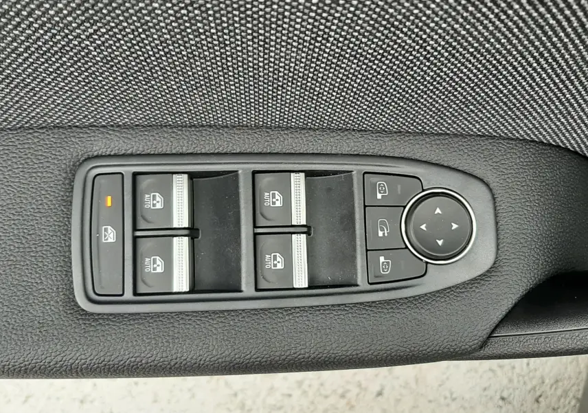 Panneau de commandes des vitres électriques et rétroviseurs sur la porte côté gauche d’un Renault Captur gris Cassiopée toit noir.