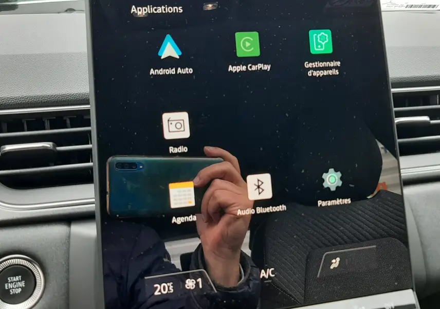 Écran tactile central du Renault Captur E-Tech 2026, affichant les applications connectées, avec tableau de bord gris en arrière-plan.