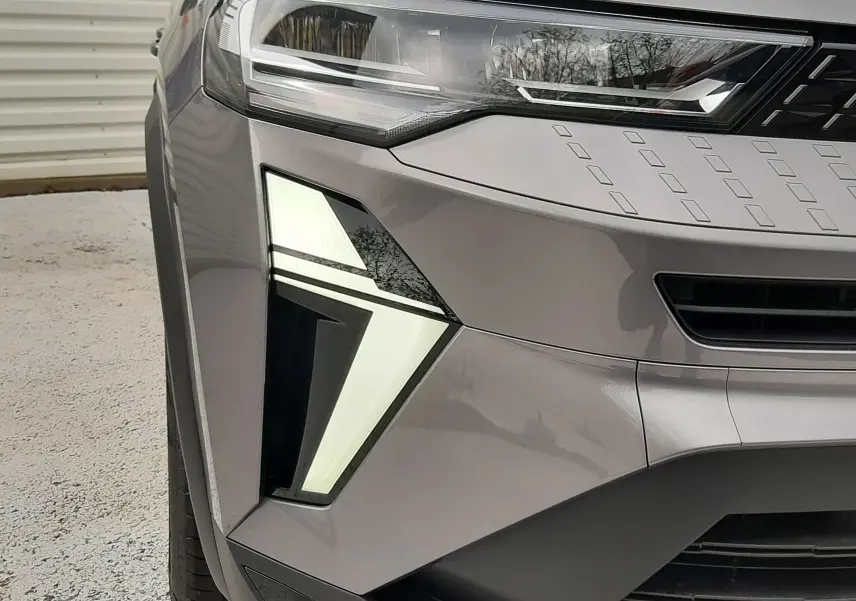 Gros plan sur l'avant gauche du Renault Captur gris Cassiopée, mettant en valeur son phare LED distinctif et la calandre noire.