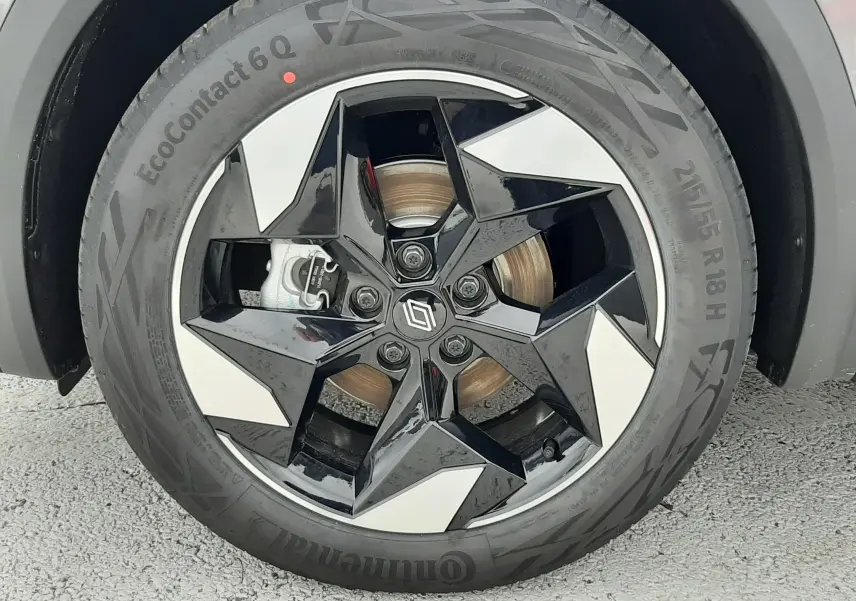 Gros plan sur la roue avant droite du Renault Captur E-Tech gris Cassiopée, jante alliage noire et argentée à design étoilé.