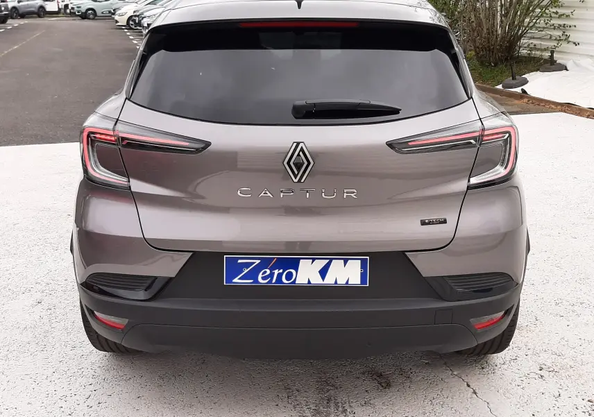 Vue arrière d'un Renault Captur E-Tech Full Hybrid gris Cassiopée avec toit noir, feux LED et plaque d'immatriculation Zero KM.