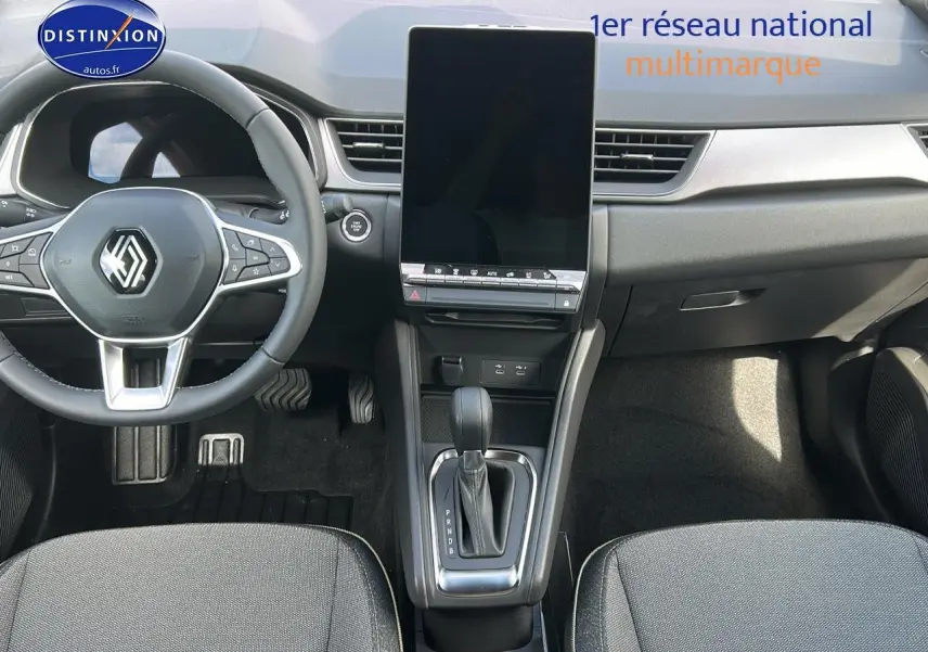 Vue intérieure avant du Renault Captur 2025 bleu iron, avec grand écran tactile vertical et volant multifonction.