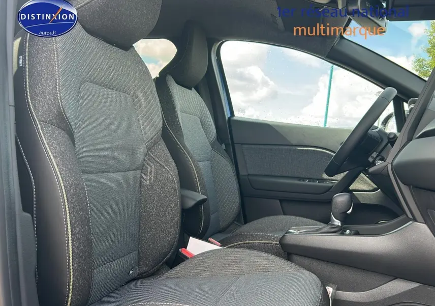 Vue intérieure côté conducteur du Renault Captur 2025, sièges tissu gris avec surpiqûres contrastées et console centrale noire.