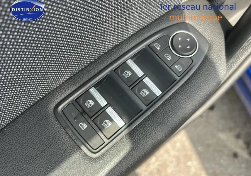 Gros plan sur les commandes des vitres électriques et rétroviseurs sur la porte avant gauche d'un Renault Captur bleu iron.