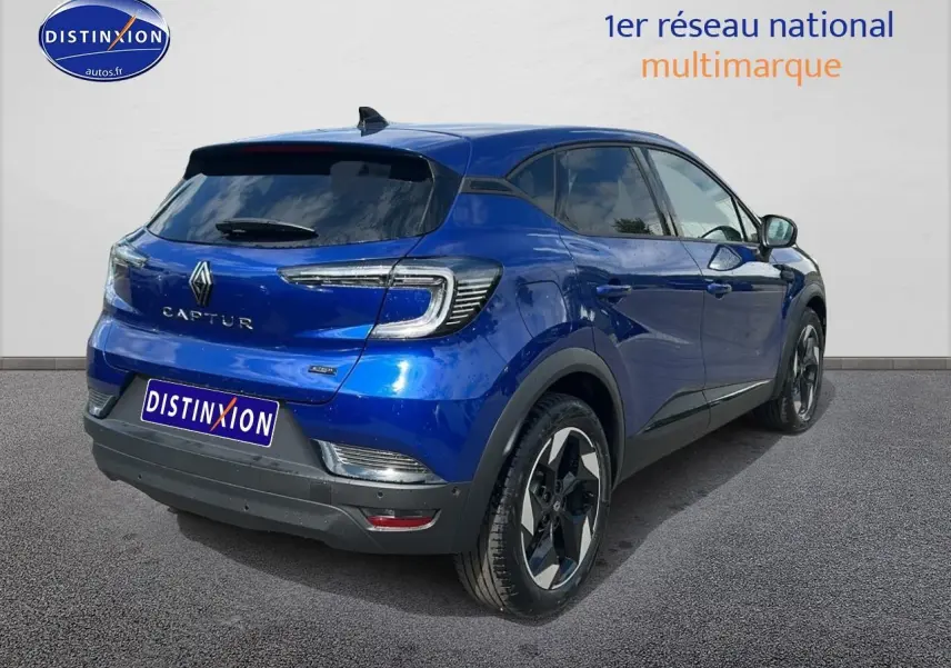 Vue 3/4 arrière droite d'un Renault Captur 2025 bleu iron avec jantes alu et vitres teintées.
