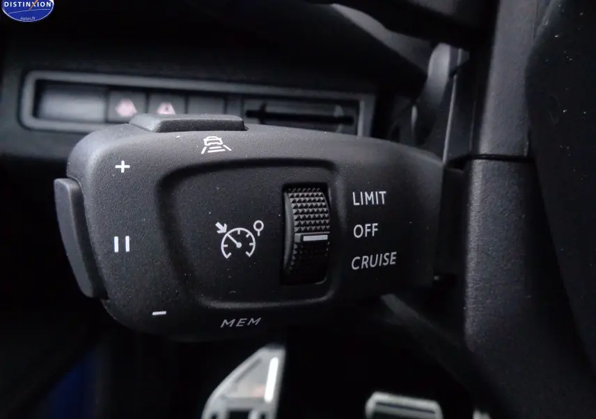 Gros plan sur la commande de régulateur de vitesse du Peugeot 3008 gris platinium, avec molette et symboles blancs.
