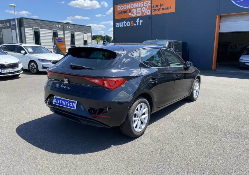 Vue 3/4 arrière droite d'une SEAT Leon 2024 noir Midnight avec vitres arrière surteintées sur parking extérieur.