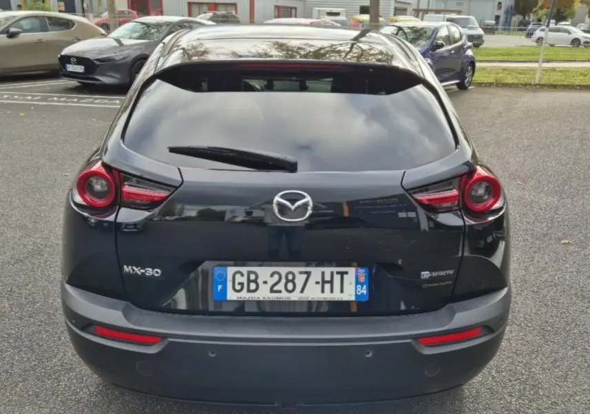 Vue arrière d'une Mazda MX-30 électrique noire de 2021 avec feux ronds et plaques d'immatriculation françaises.