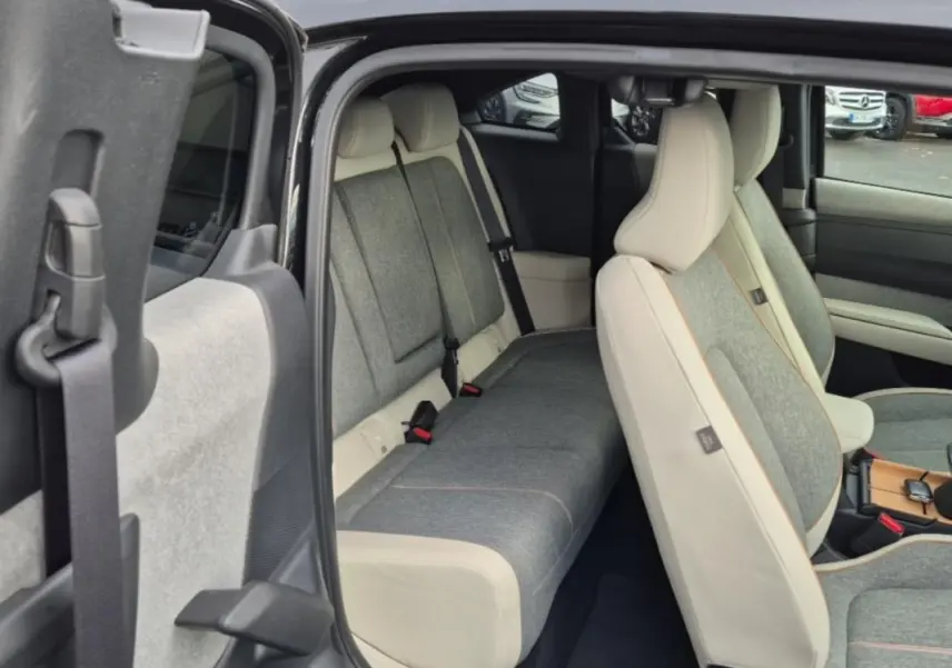 Intérieur de la Mazda MX-30 2021, vue côté gauche sur les sièges avant et arrière en tissu gris et cuir clair.
