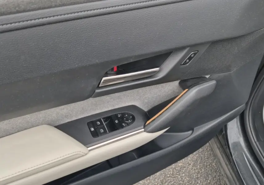 Gros plan sur la garniture de la porte côté gauche d'une Mazda MX-30 2021 avec sellerie claire et insert bois.