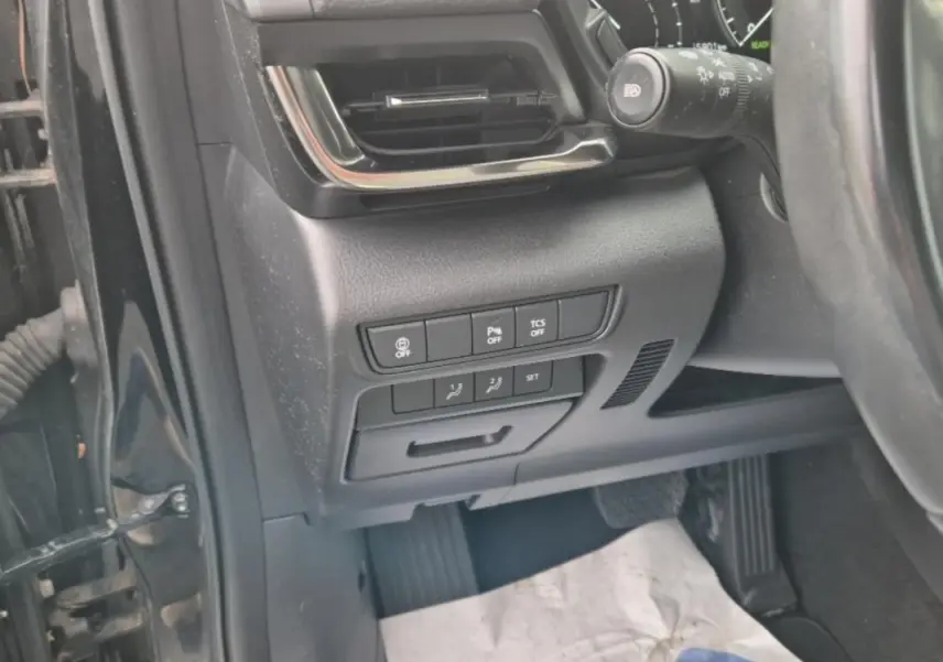 Vue rapprochée côté gauche du tableau de bord noir du Mazda MX-30 électrique, montrant les commandes de sécurité et ventilation.