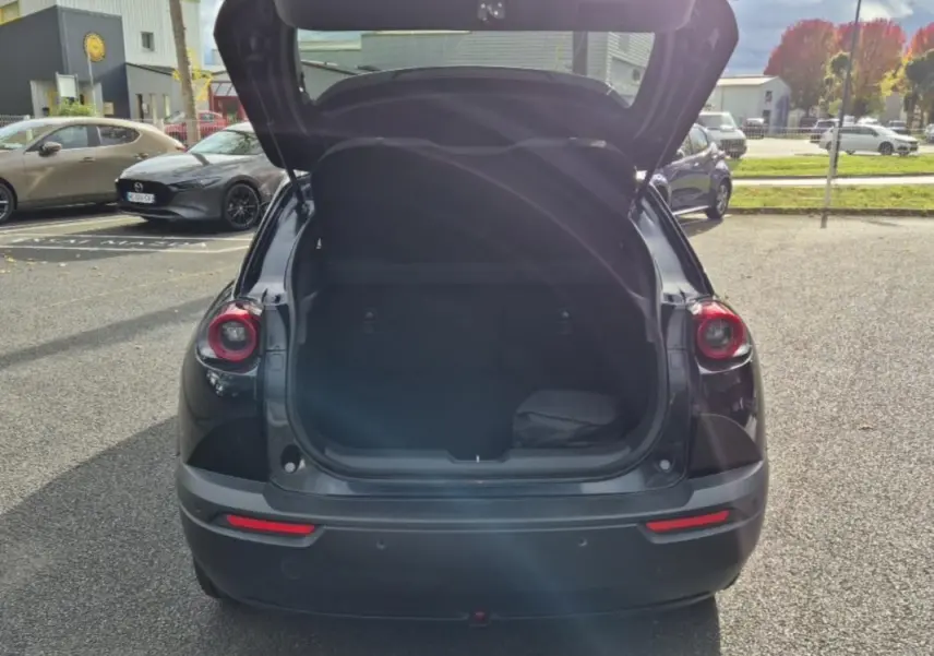 Vue arrière du Mazda MX-30 électrique noir 2021 avec coffre ouvert, soulignant ses feux ronds caractéristiques.