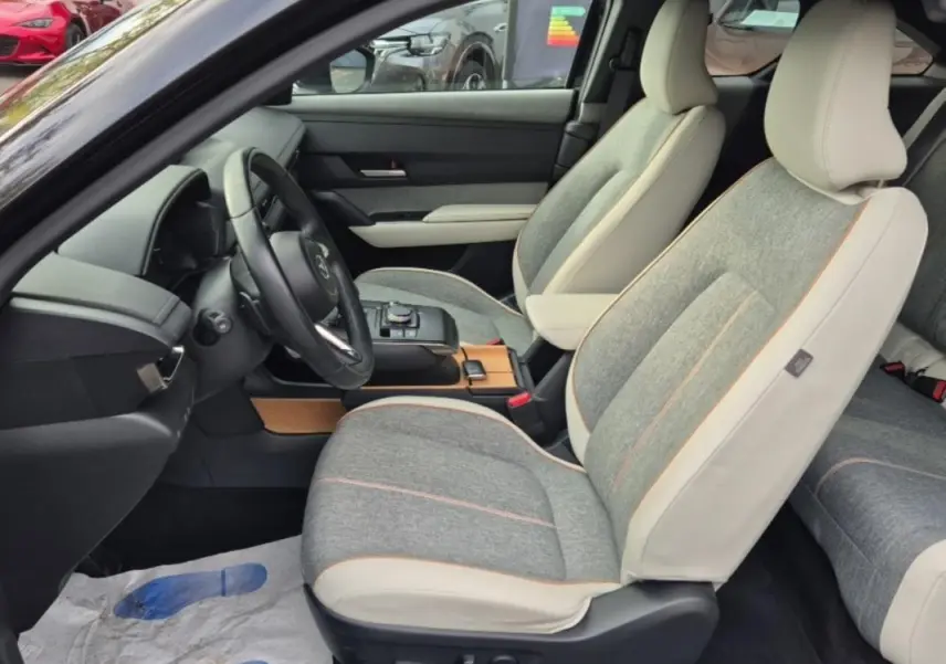 Intérieur du Mazda MX-30 First Edition 2021, vue côté conducteur sur les sièges gris et beige avec sellerie Modern Confidence.