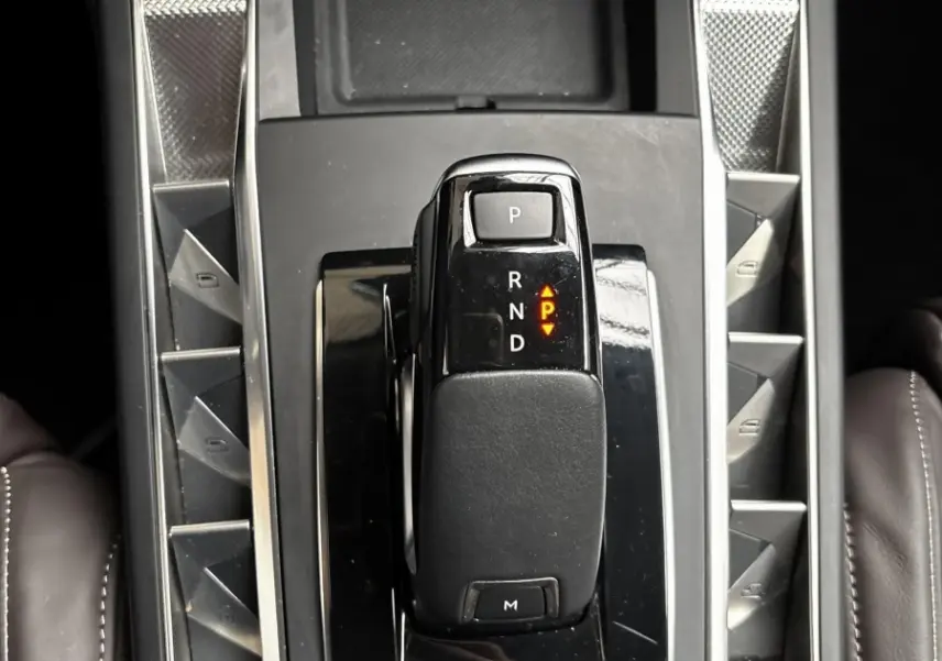 Vue plongeante sur la console centrale noire du DS3 2024, avec levier de vitesses automatique et boutons en finition métal brossé.