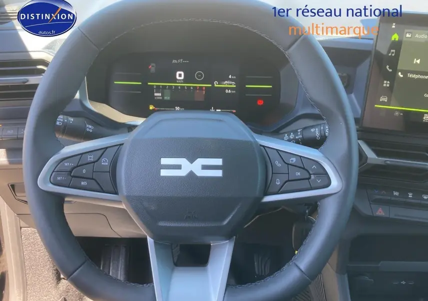 Vue rapprochée du volant noir multifonction du Dacia Duster 2025 avec tableau de bord numérique et écran tactile latéral.