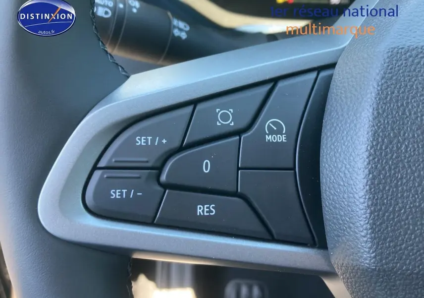 Gros plan sur les commandes multifonctions noires du volant du Dacia Duster 2025, avec boutons de réglage et mode.