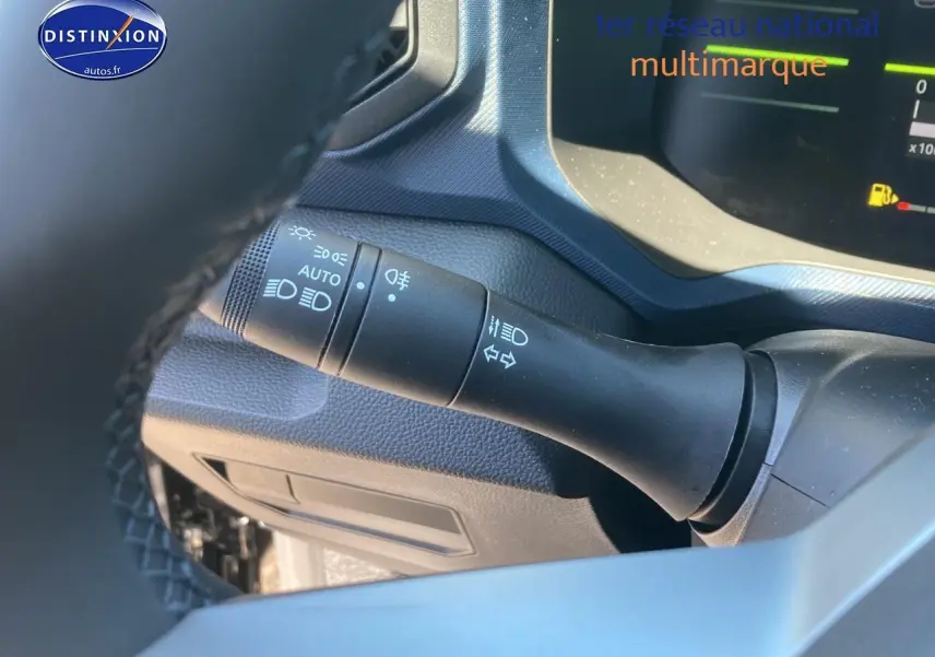 Détail du commodo d'éclairage noir à gauche du volant dans le tableau de bord du Dacia Duster noir 2025.
