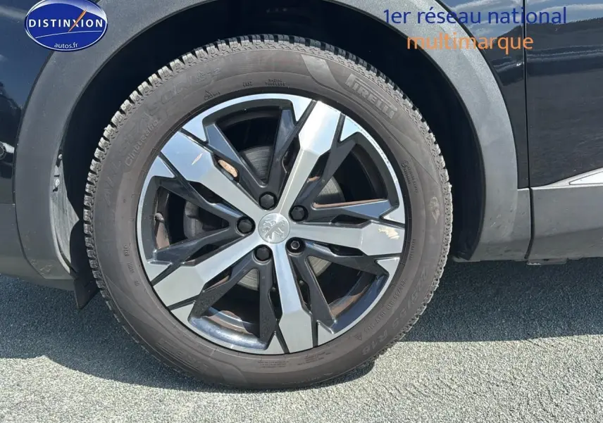Gros plan sur la jante alu noire et argentée du côté avant droit d'un Peugeot 5008 noir métal 2022.
