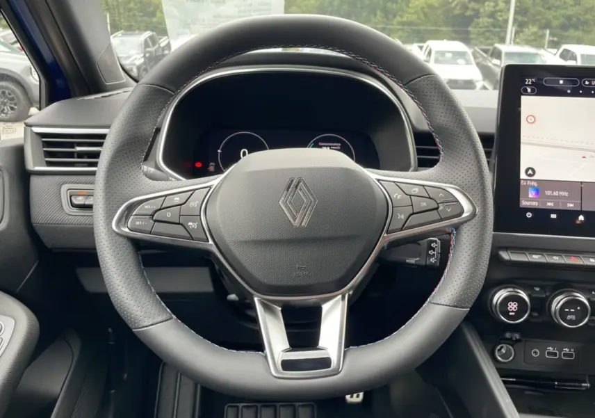 Vue centrée du volant perforé de la Renault Clio V TCE 90 Esprit Alpine 2025 avec tableau de bord numérique et écran tactile.