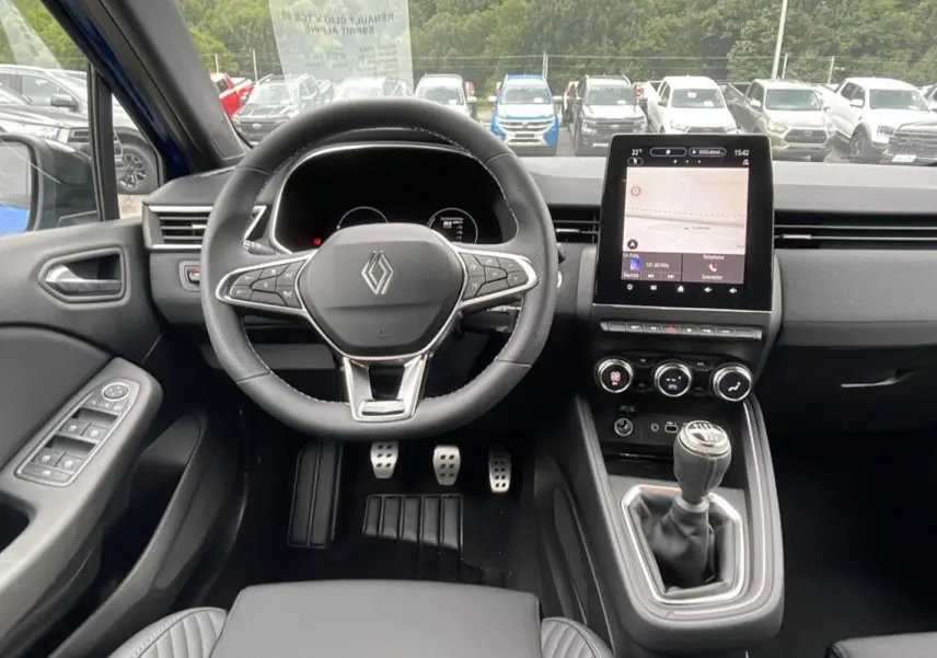Intérieur de la Renault Clio V TCE 90 Esprit Alpine 2025 en bleu iron, vue frontale sur le volant, tableau de bord et levier manuel.
