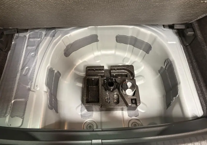 Coffre ouvert du SEAT Arona 2024 montrant la roue de secours et le rangement intérieur gris métallique.