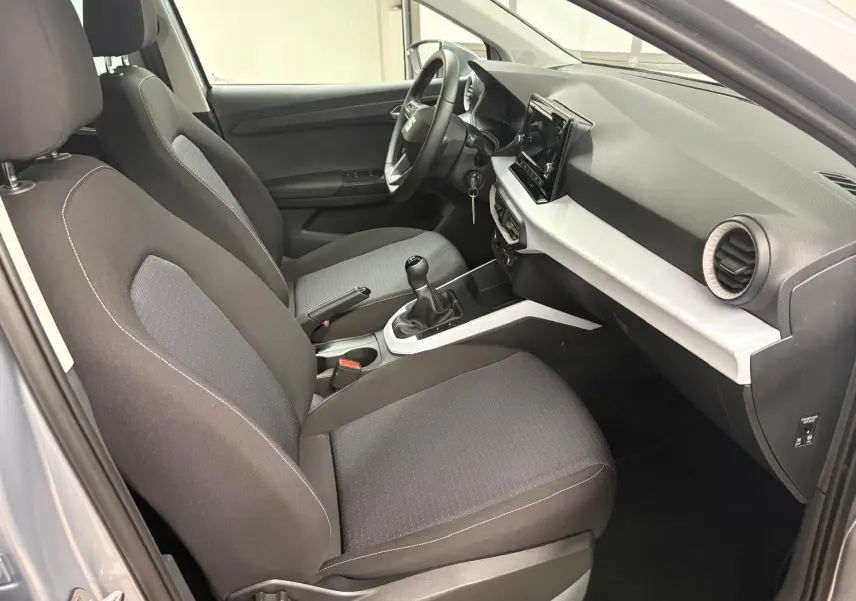 Intérieur avant droit du SEAT Arona 2024 gris urbain, sièges tissu noirs et console centrale avec boîte manuelle.