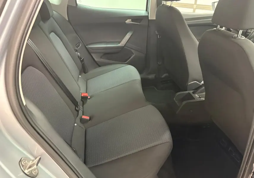 Vue intérieure arrière gauche des sièges tissu gris du SEAT Arona 2024 avec portières ouvertes et vitres surteintées.
