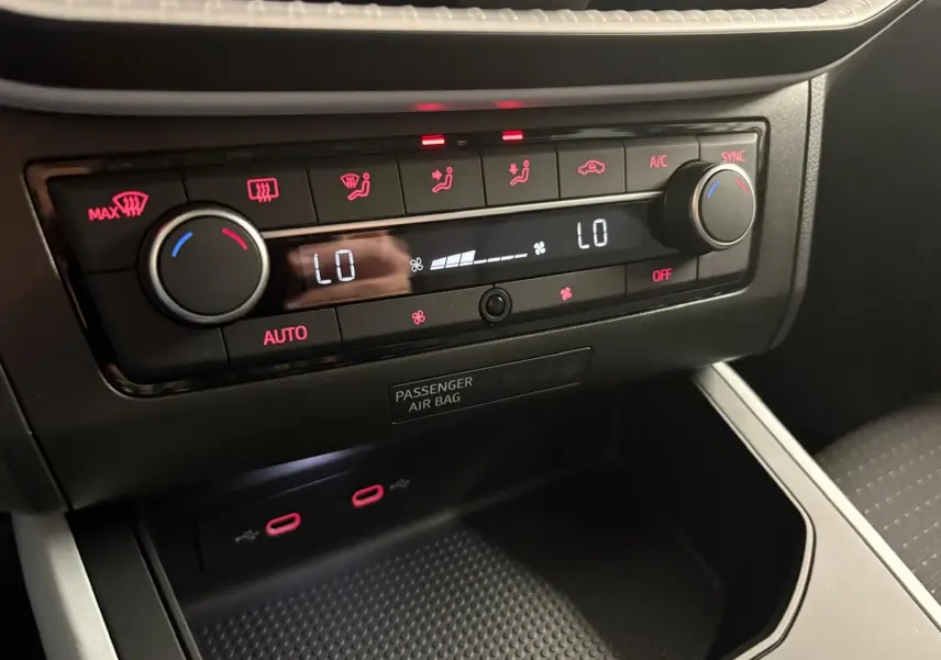 Tableau de bord du SEAT Arona 2024 montrant la climatisation digitale avec commandes rétroéclairées en rouge.