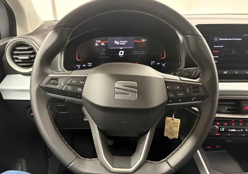 Vue intérieure centrée sur le volant cuir du SEAT Arona 2024 avec commandes intégrées et tableau de bord digital.