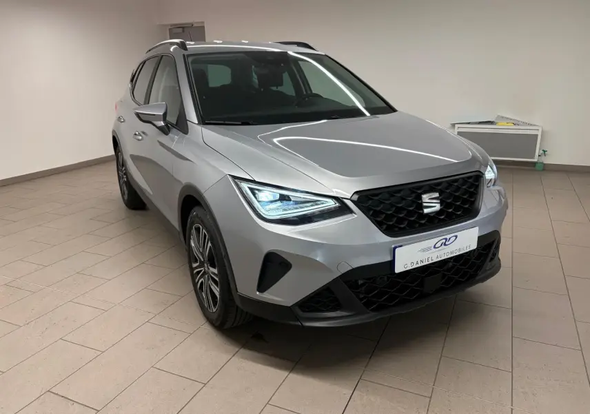 SEAT Arona 2024 gris urbain en 3/4 avant droit avec vitres arrière surteintées et calandre noire.