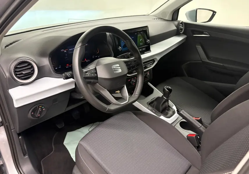 Intérieur avant droit du SEAT Arona 2024 avec volant multifonction, tableau de bord numérique et boîte manuelle.