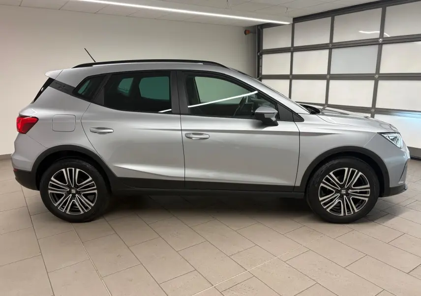 Profil droit d'un SEAT Arona 2024 gris urbain avec vitres arrière surteintées et jantes alliage en intérieur neutre.