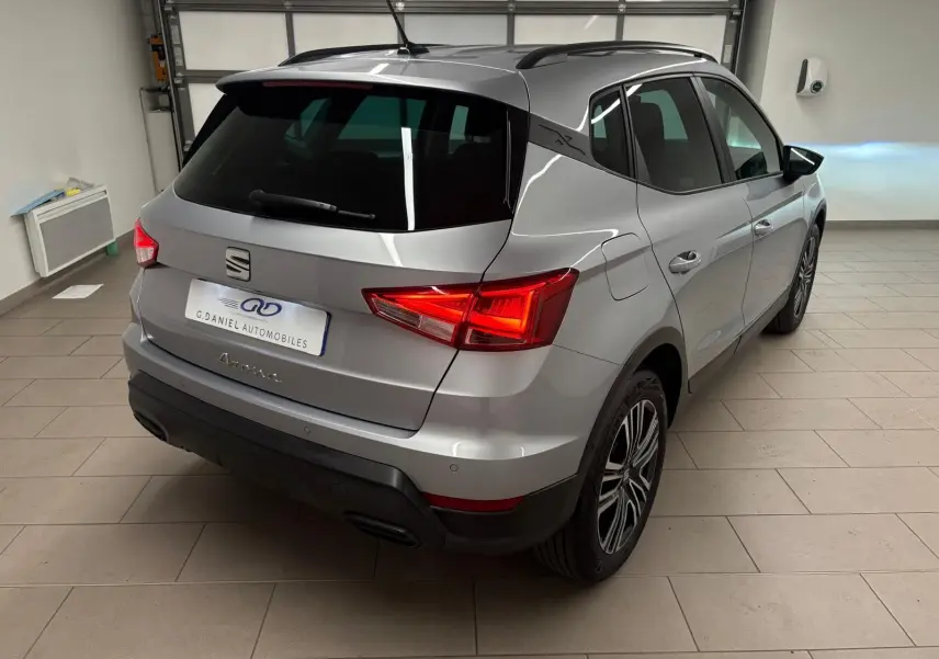 SEAT Arona gris urbain en 3/4 arrière droit, vitres arrière surteintées et feux arrière allumés en intérieur.