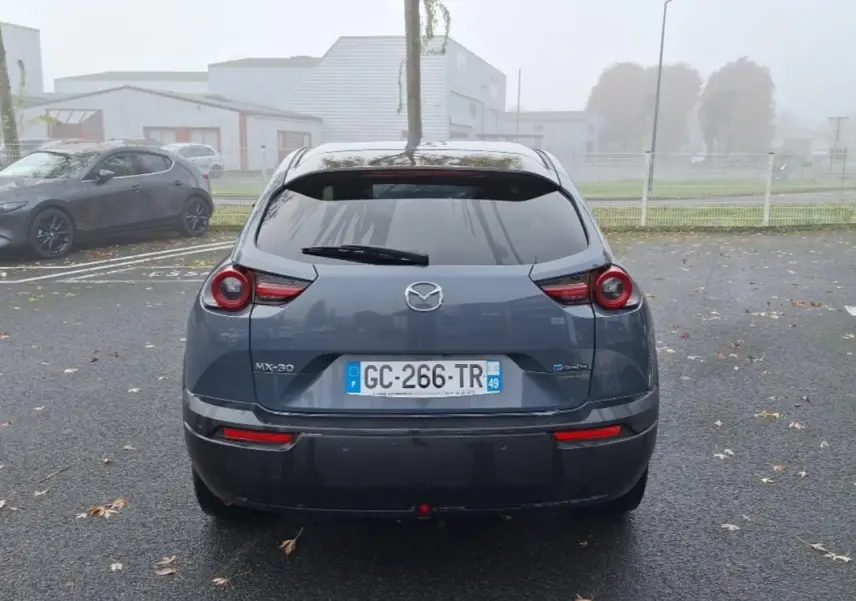 Vue arrière d'une Mazda MX-30 gris électrique 2021 avec feux ronds caractéristiques et plaque d'immatriculation française.