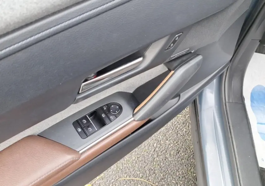 Détail de la porte avant gauche gris clair du Mazda MX-30 2021 avec commandes de vitres et insert marron.