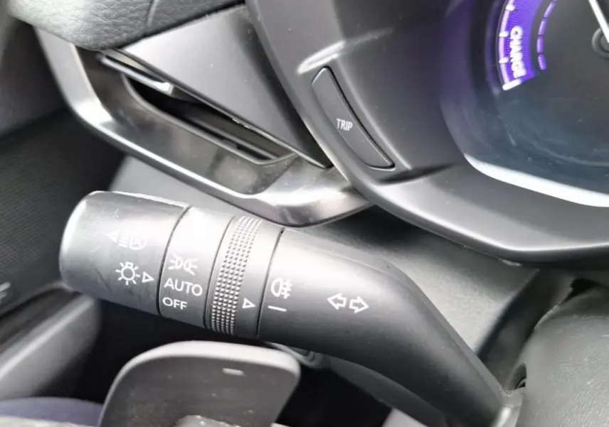 Gros plan sur la commande des feux et clignotants côté gauche du tableau de bord gris d'une Mazda MX-30 électrique 2021.