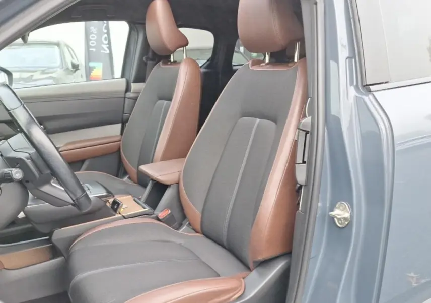 Vue intérieure côté gauche du Mazda MX-30 gris 2021, sièges bi-matière marron et tissu gris, volant et console visibles.