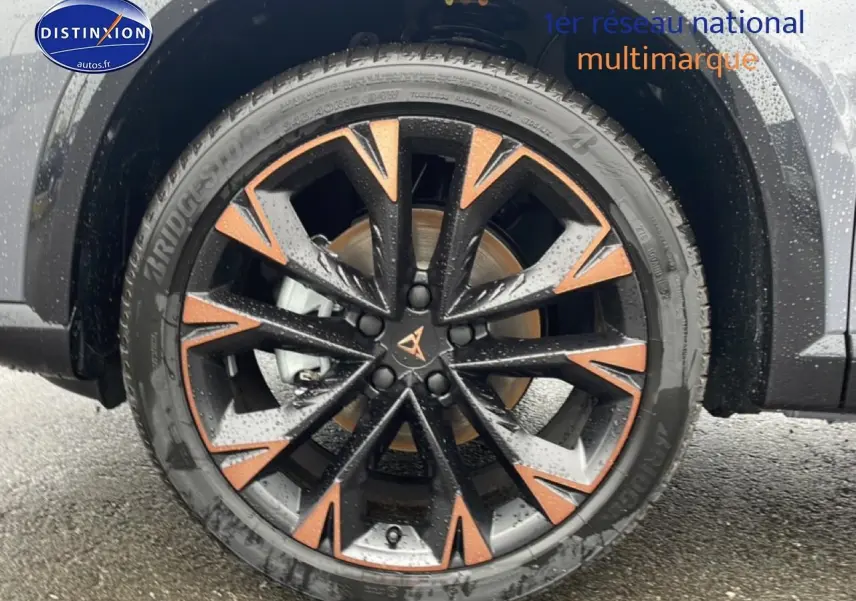 Gros plan sur la jante noire et cuivre du CUPRA Formentor gris graphene, avec pneu Bridgestone humide.