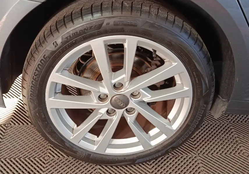 Gros plan sur la roue avant droite d'une Audi A3 gris foncé, avec jante alliage argentée et pneu Bridgestone.