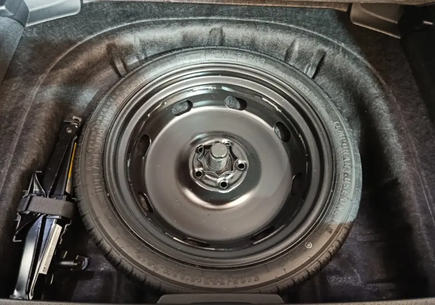 Vue plongeante sur la roue de secours noire dans le coffre d'une Audi A3 35 TDI 150 S Tronic Business Line gris foncé.