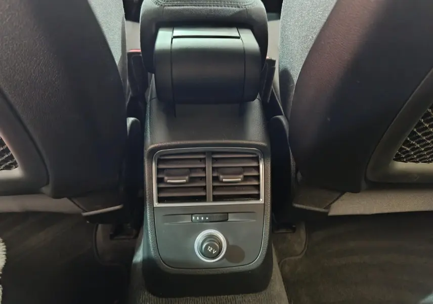 Vue rapprochée de la console centrale arrière noire avec bouches d’aération et prise 12V de l’Audi A3 gris foncé.