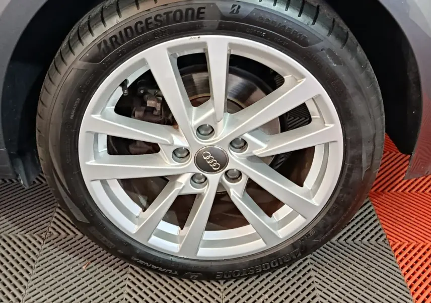 Gros plan sur la roue avant droite d'une Audi A3 gris foncé, jante alliage à 10 branches et pneu Bridgestone.