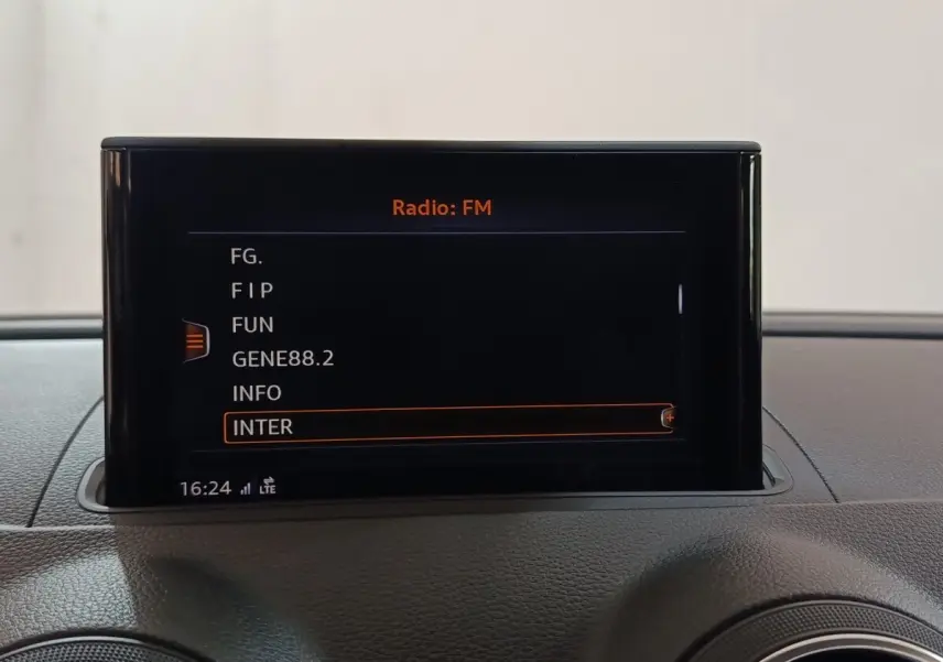Écran central affichant les stations radio FM dans l’habitacle d’une Audi A3 gris foncé, vue de face.