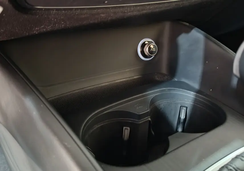 Vue rapprochée de la console centrale noire de l’Audi A3 35 TDI avec prise 12V et porte-gobelets intégrés.