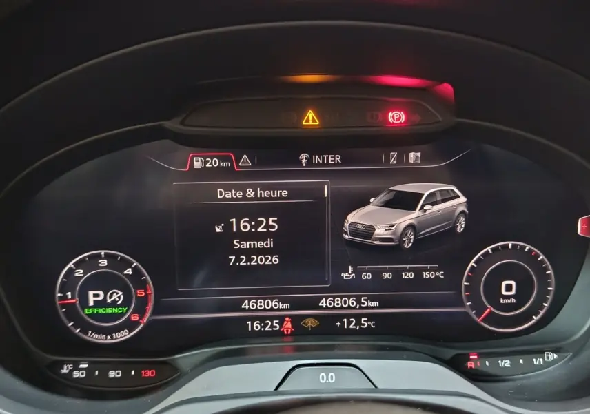 Vue rapprochée du tableau de bord numérique d’une Audi A3 gris foncé, affichant date, heure et indicateurs de conduite.